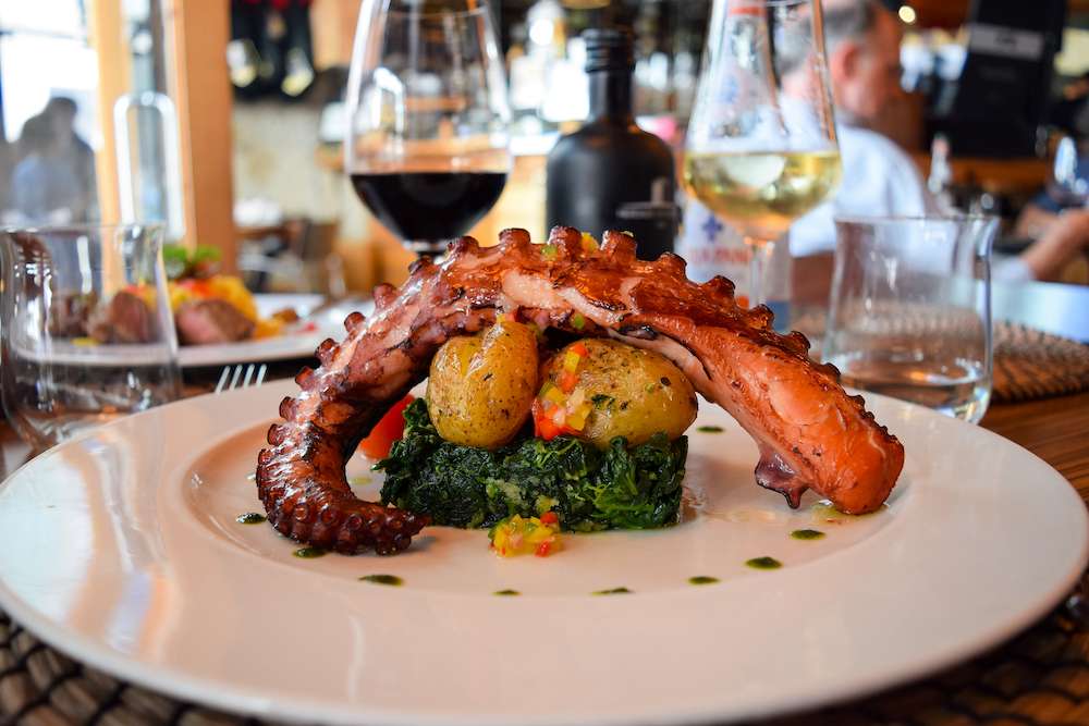 Restaurant, lifestyle, travel food - grilled octopus, potato, spinach, red wine glass, white wine